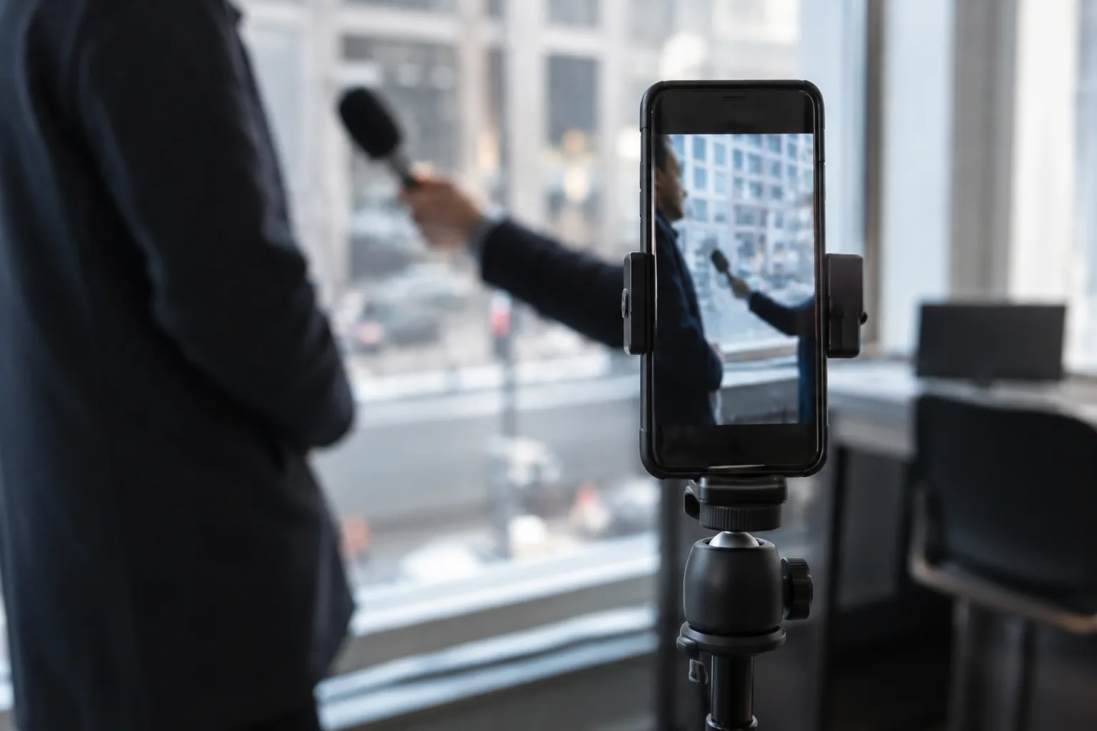 Un smartphone vertical installé sur un trépied dans un espace de travail journalistique.